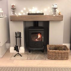 a wood burning stove sitting inside of a living room next to a basket filled with firewood