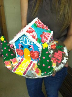 a woman holding a cake shaped like a house