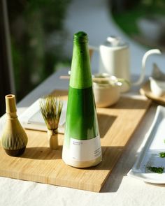 a table topped with plates and vases covered in green liquid on top of a wooden cutting board