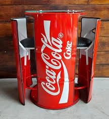 an old coca - cola machine is sitting on the floor next to a wooden wall