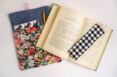 an open book sitting on top of a table next to a pair of pencils