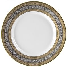 a white and gold plate with an intricate design on the rim, against a white background