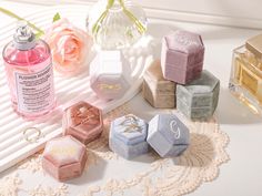 several different colored soaps and rings on a doily next to a bottle of perfume