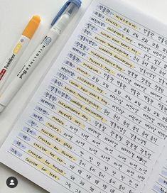 two pens sitting on top of an open notebook with chinese characters written in the pages