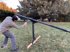 a man standing on top of a wooden seesaw in the middle of a field