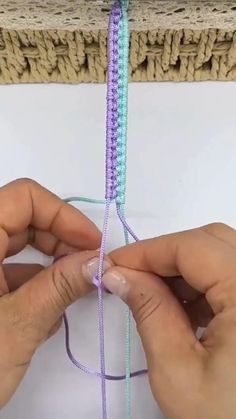 two hands are working on a piece of yarn