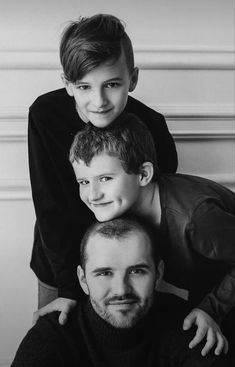 a man and two boys are posing for a black and white photo with their arms around each other