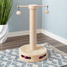 a cat tree with two balls hanging from it's posts and a rug on the floor