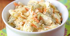 a white bowl filled with coleslaw and carrots on top of a table