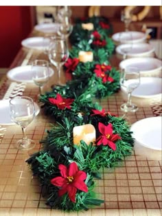 the table is set for christmas dinner with candles and poinsettis on it