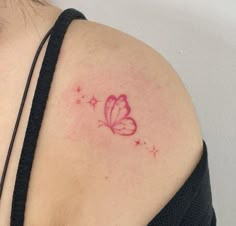 a small butterfly tattoo on the back of a woman's shoulder