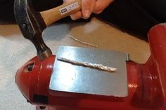 a person using a hammer to cut metal on top of a red fire hydrant