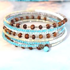 Bohemian Beachy Vibes Wooden Spiral Stack Wire Beaded Bracelet Whimsical Beachy Colors In Blues, White, Clear And Brown Wooden Beads. One Size Fits Most. So Easy To Put On And Wear. #Beadedbracelet #Multicolorbeads #Stackedbracelet #Wirecuff Beachy Beach Seedbeads Bohemian Wrap Bracelet With Round Beads For Summer, Bohemian Wrap Bracelet With Colorful Beads For Summer, Beaded Wrap Bracelet For Beach In Summer, Bohemian Spiral Hand Wrapped Bracelets, Bohemian Colorful Beads Wrap Bracelet For Summer, Bohemian Summer Wrap Bracelet With Colorful Beads, Beach Wrap Bracelet With Tiny Beads, Bohemian Beaded Wrap Bracelet For Beach, Blue Wrap Bracelet For Beach