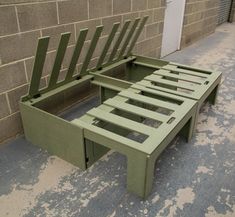 a green bench sitting next to a brick wall