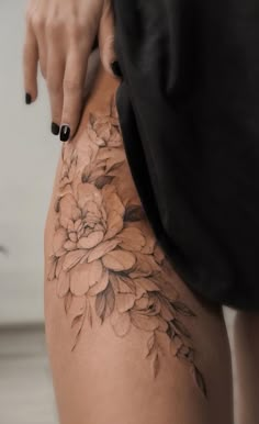 a woman's thigh with flowers on it and her hand holding the lower part of her leg