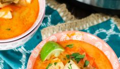 two bowls filled with soup on top of a blue and white table cloth next to an orange bowl