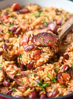 a skillet filled with rice and beans on top of a wooden spoon in it