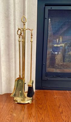 a gold plated metal stand with two brooms and a brush on the floor in front of a fireplace