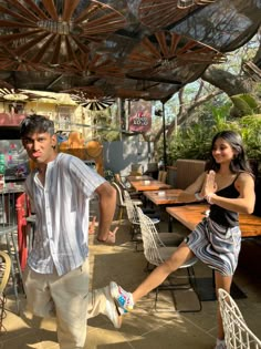 a man and woman dancing in an outdoor area with tables, chairs and umbrellas