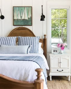 a bed with blue and white pillows in a bedroom next to a window that has pictures on the wall above it