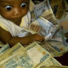 a baby is sitting on top of money and looking at the camera with big eyes