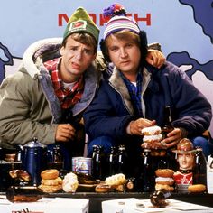 two men sitting at a table with doughnuts and beer