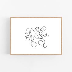 a black and white drawing of an octopus on a white wall above a wooden frame