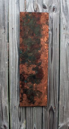 an old rusty piece of metal sitting on the side of a wooden fence with peeling paint