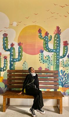 a woman sitting on a bench in front of a mural