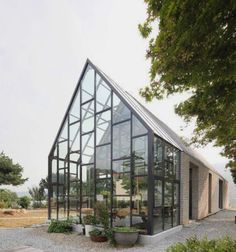 a glass house sitting in the middle of a gravel field next to a picnic table