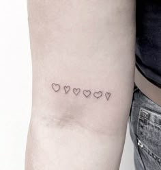 a woman's arm with four small hearts on the left side of her arm