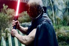 a man dressed as darth vader holding a light saber in his right hand