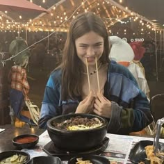 a woman eating food with chopsticks in front of her at an outdoor event