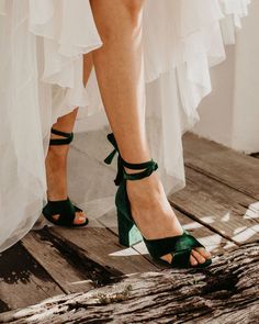 a woman wearing green high heels standing on a wooden floor