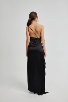 the back of a woman wearing a long black dress with one shoulder draped over it