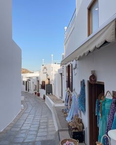 an alley way with white buildings and clothes on display