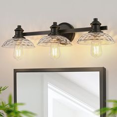 a bathroom vanity light with three clear glass shades on the top and bottom lights above it