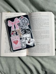 an open book with stickers on it laying on top of a bed next to a blanket