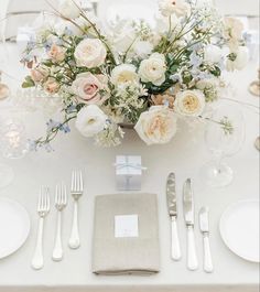 a table set with silverware and white flowers