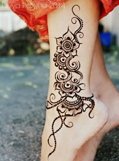 a woman's foot with henna tattoos on it