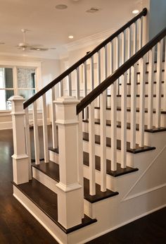 a white staircase with black handrails and wood flooring in a large home