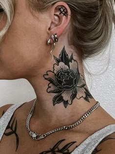 a woman with a flower tattoo on her neck and behind her ear is a chain