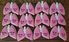 decorated cookies with pink and white icing on a cooling rack, some have faces drawn on them