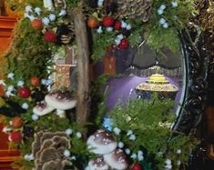 a christmas wreath with mushrooms, pine cones and other holiday decorations on it in front of a mirror