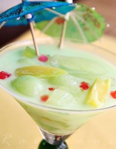 a green drink with fruit and umbrellas in it