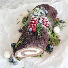 a piece of cake decorated with berries and greenery on top of white wax paper