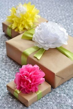 three gift boxes with flowers on them sitting on the floor next to each other and wrapped in brown paper