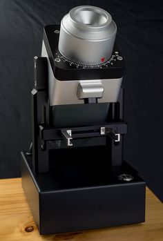 a camera sitting on top of a wooden table next to a black box with a silver object in it