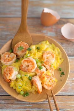 shrimp and rice dish with chopsticks on wooden table next to egg shell shells