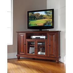 a flat screen tv sitting on top of a wooden entertainment center next to a window